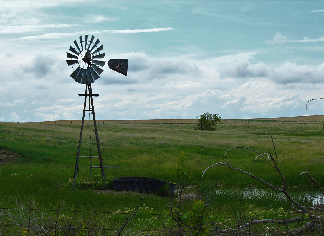 Kiowa KS Insurnace - windmill in the field with blue sky and green grass in Barber County Kansas out in the country.